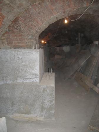 Фотография внутренней кирпичной стены подвала здания после реконструктивных работ по углублению подвала с устройством железобетонной вертикальной прижимной стенки.
